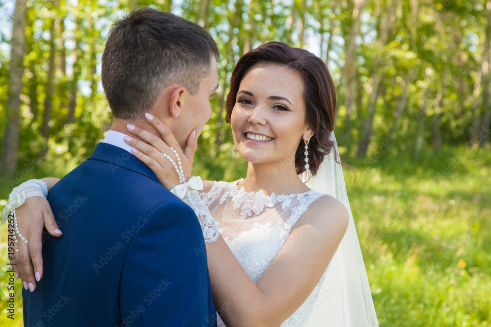 Beautiful happy newlyweds on walk. Summer wedding. Emotions and tenderness of the bride Beautiful happy newlyweds on walk. Summer wedding. Emotions and tenderness of the bride