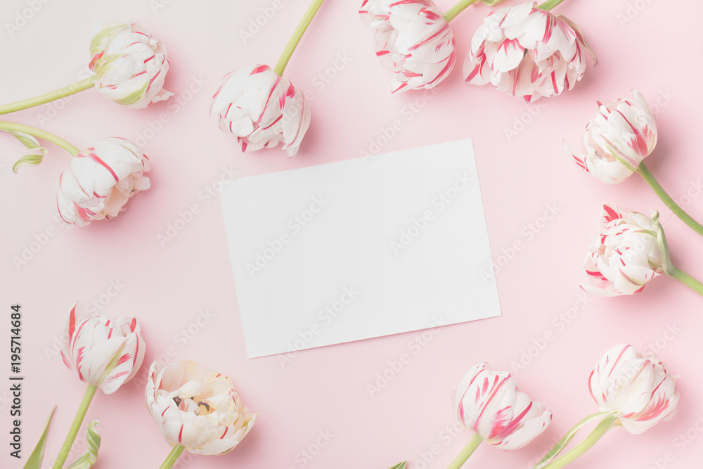 Spring morning concept. Flat-lay of flowers and card over light pink background, top view with space for your text