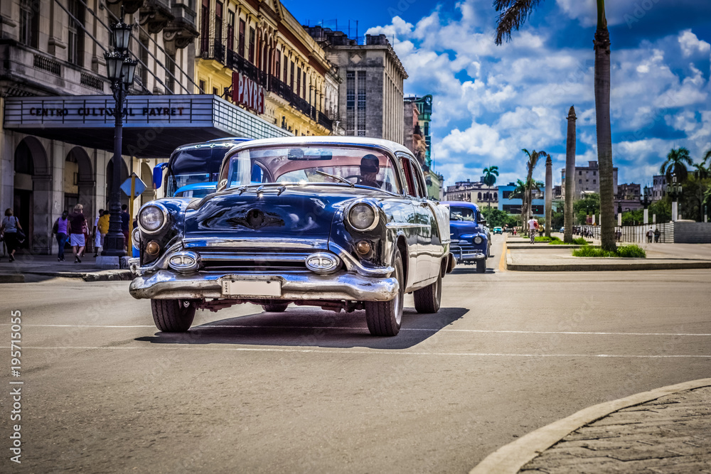 Fototapeta HDR - Schwarzer Oldtimer mit weißem Dach fährt auf der Hauptstraße an der historischen Häuserfront vorbei - Serie Kuba Reportage