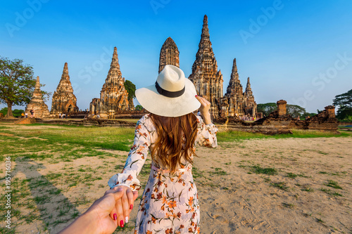 Woman holding man's hand and leading him to Ayutthaya Historical Park, Wat Chaiwatthanaram Buddhist temple in Thailand. photo