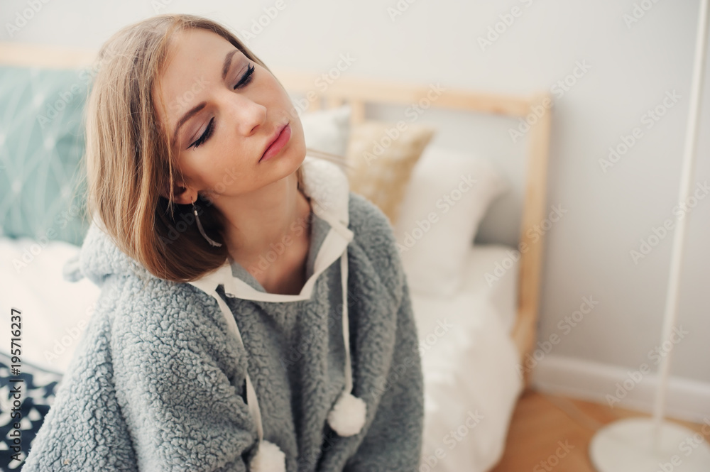 young beautiful woman relaxing at home on the bed, wearing funny grey hoodie. Waking up in lazy weekend morning young beautiful woman relaxing at home on the bed, wearing funny grey hoodie. Waking up in lazy weekend morning