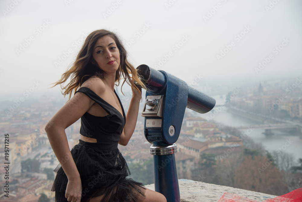 Sexy girl dressed in black, with spyglass pointing at the city