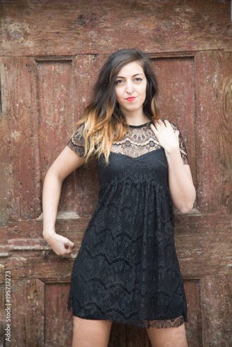 very sensual girl with old door in the background, with dress in black lace