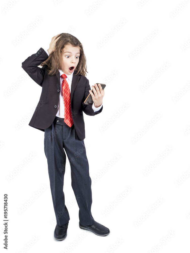 Portrait of a little Caucasian boy holding a two-handed phone with a crazy shocked look and an open mouth in surprise Portrait of a little Caucasian boy holding a two-handed phone with a crazy shocked look and an open mouth in surprise