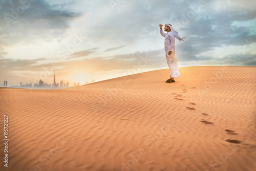 Arabic man with traditional emirates clothes walking in the desert