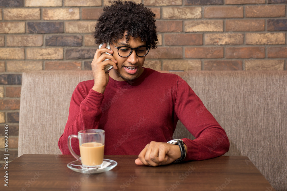 Handsome young businessman talking on the phone at a cafe Handsome young businessman talking on the phone at a cafe