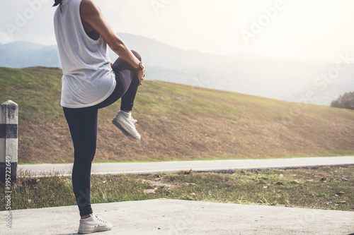 Obraz na plátně Athlete woman doing some stretching exercises legs before running on outdoor