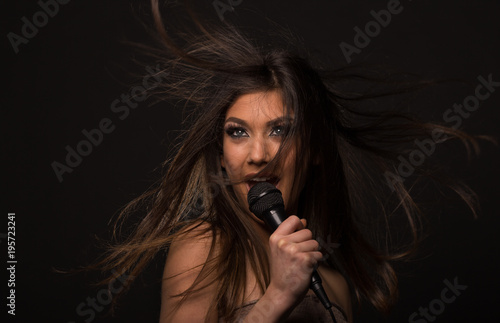 Beautiful young girl singing into a microphone with hair flying
