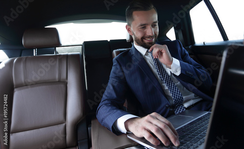 businessman reads information on laptop while sitting in car © ASDF