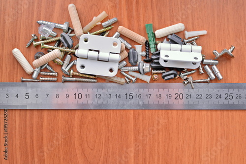Kit of wooden, metal and plastic furniture parts and ruler on the board