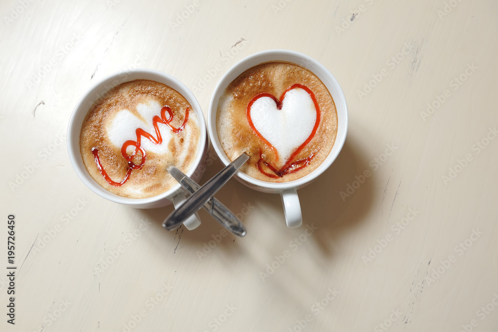 Two cups of coffee on the table with a picture of the heart and an inscription - love Two cups of coffee on the table with a picture of the heart and an inscription - love