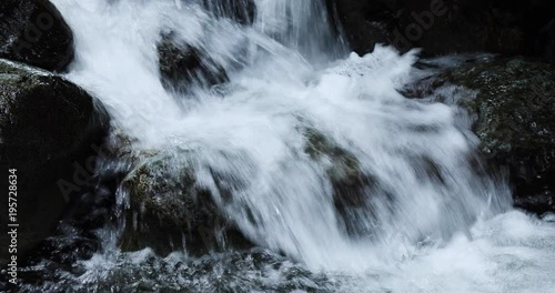 view of a stream flowing down from stickle tarn in langdale in the lake district national park in the north of england showing the blurred water moving down over dark rock photo