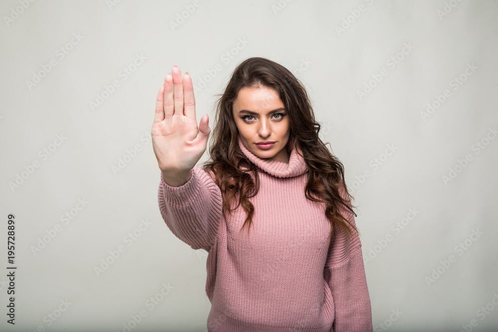 Portrait of a serious young woman standing with outstretched hand showing stop gesture isolated over white background Portrait of a serious young woman standing with outstretched hand showing stop gesture isolated over white background