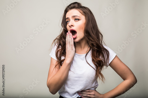 Young woman yawing isolated on gray background