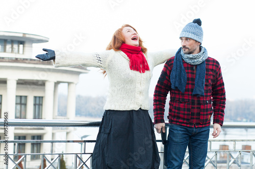 Very happy woman crying on the bridge and surprised man. Screaming red hair woman and guy looking to her. Surprised man looked at bawling girlfriend near of bridge barrier. Lady with opened mouth hug