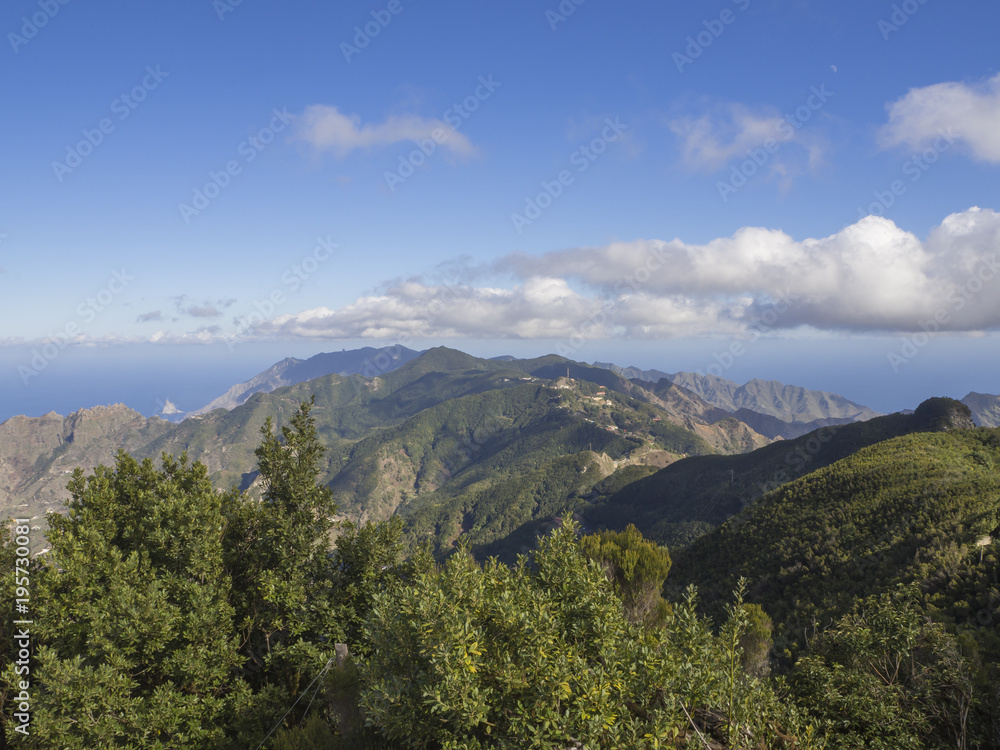 view point Amogoje, green hills with rock in the sea El Draguillo in anaga mountain, tenerife  canary island spain with dramatic blue sky white clouds background