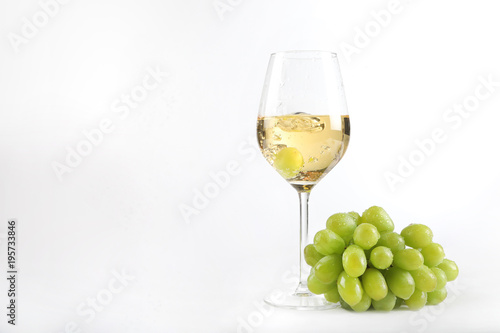 Weiswein in einem Glas mit einer Traube im Glas und Weintrauben nebenliegend
