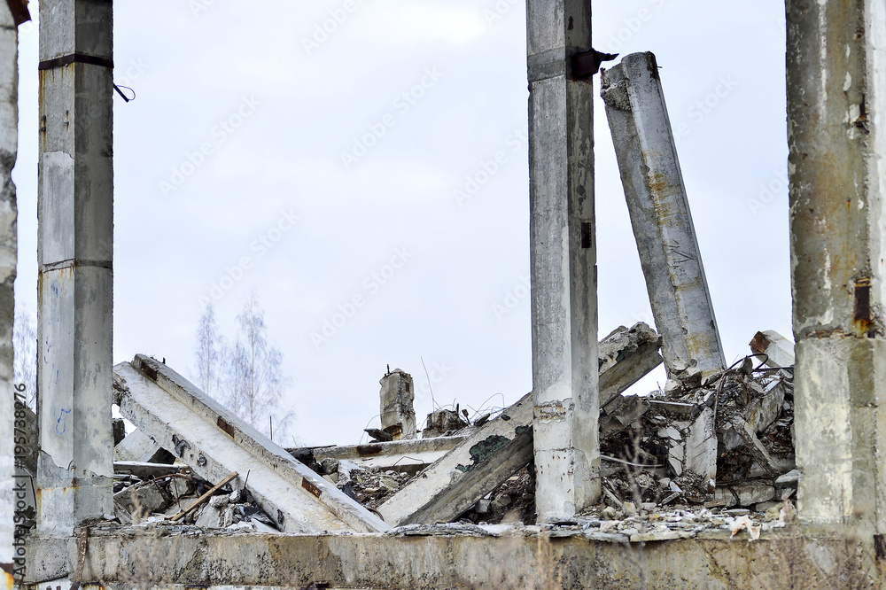 Fototapeta premium Remains of the destroyed industrial building. Large concrete piles continue to hold the body of the large concrete buildings, while others look at the sky.