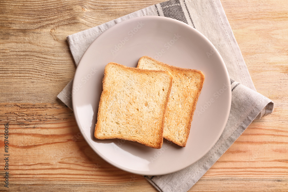 Plate with tasty toasted bread on wooden table