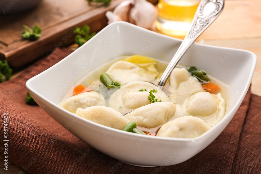 Bowl with tasty broth and dumplings on table Bowl with tasty broth and dumplings on table