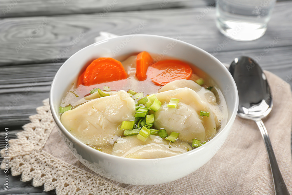 Bowl with tasty broth and dumplings on table
