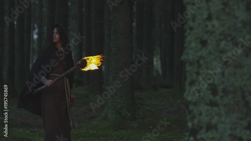 Woman holding a fire staff in the woods