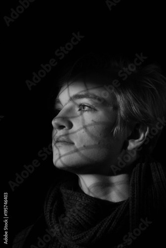 the beautiful boy with the shadow of the lattice on the face