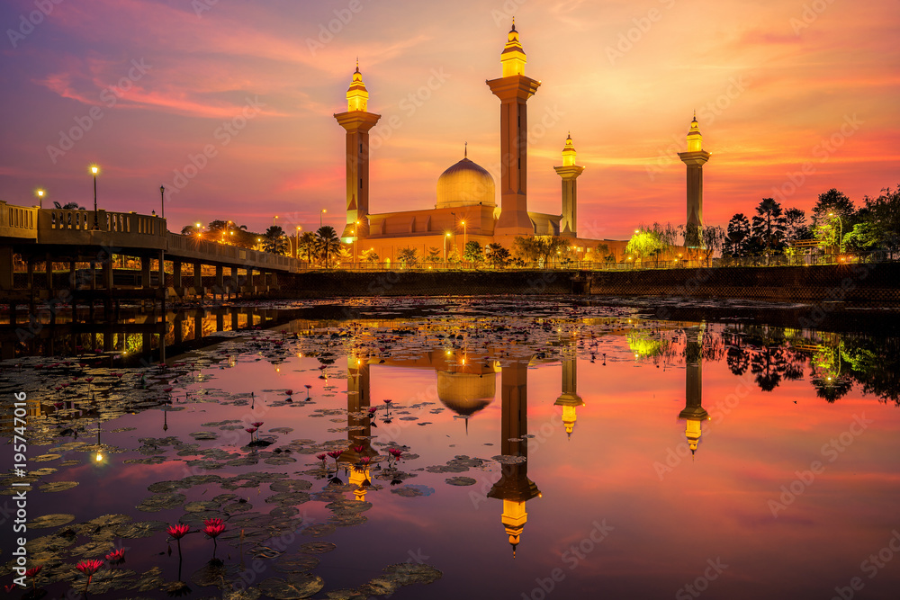 Fiery sunrise over Tengku Ampuan Jemaah Mosque at Bukit Jelutong, Kuala lumpur, Malaysia with beautiful lotus in the lake.