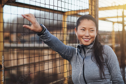 Sporty Asian woman listening to music on earphones before exerci photo