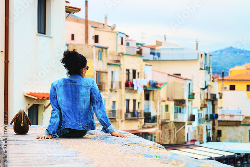 Young woman sitting Cefalu old town streets Sicily