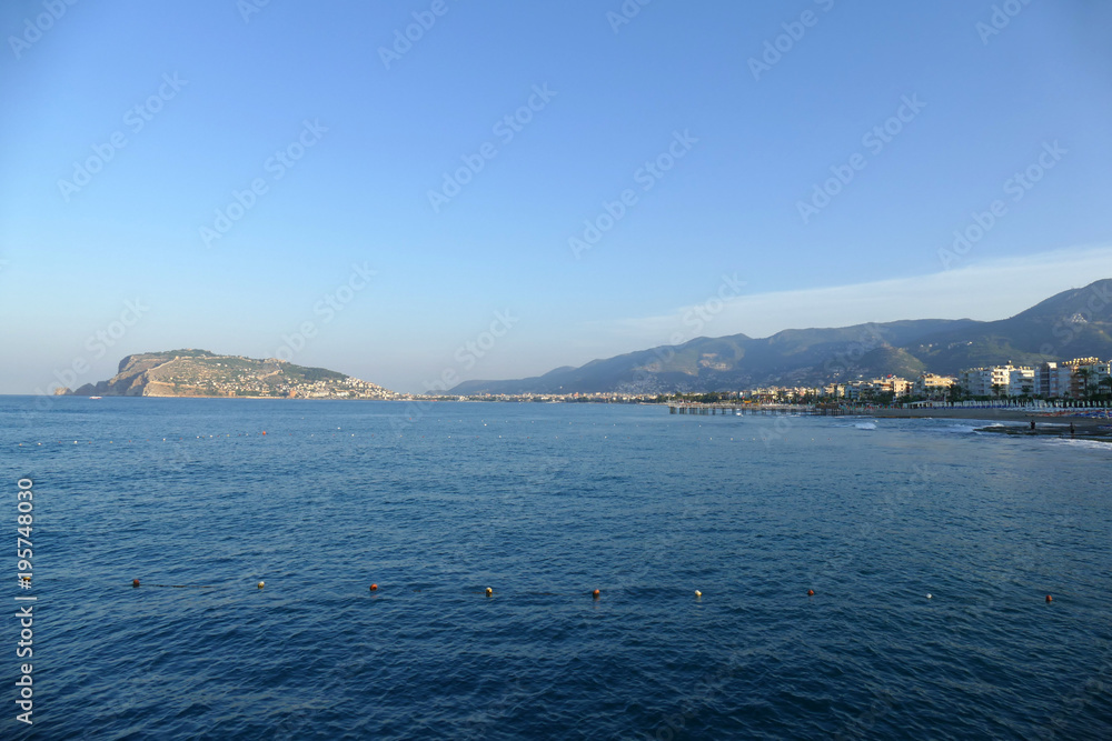 Deep blue water with mountains ahead and blue sky with clouds, horizontal view