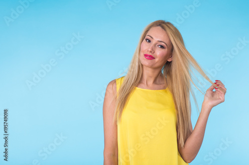 beauty fashion summer portrait of blonde woman with red lips and yellow dress on blue background with copy space