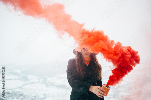Hipster girl with red smoke bomb send smoke signal photo