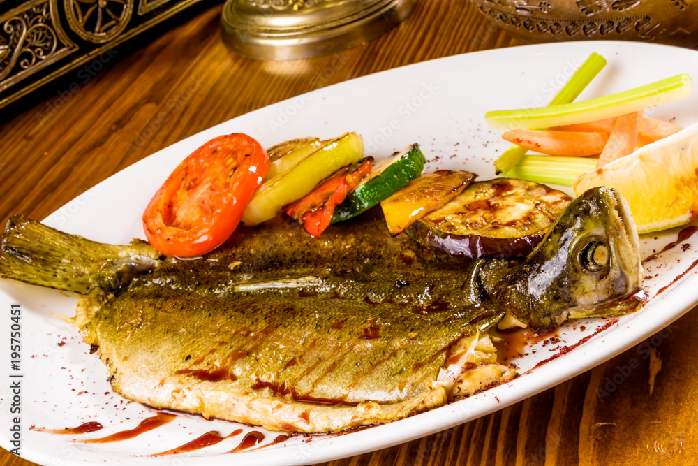 Whole trout with grilled vegetables on white plate Whole trout with grilled vegetables on white plate