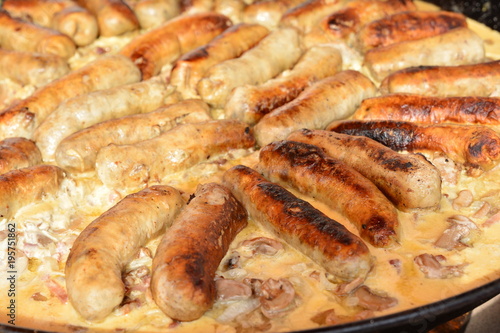 Fried sausages with mushrooms in a large frying pan on the market