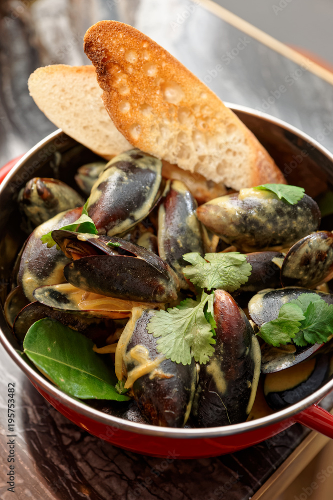 Mussels cooked with curry and served in metal pot, Asian food Mussels cooked with curry and served in metal pot, Asian food