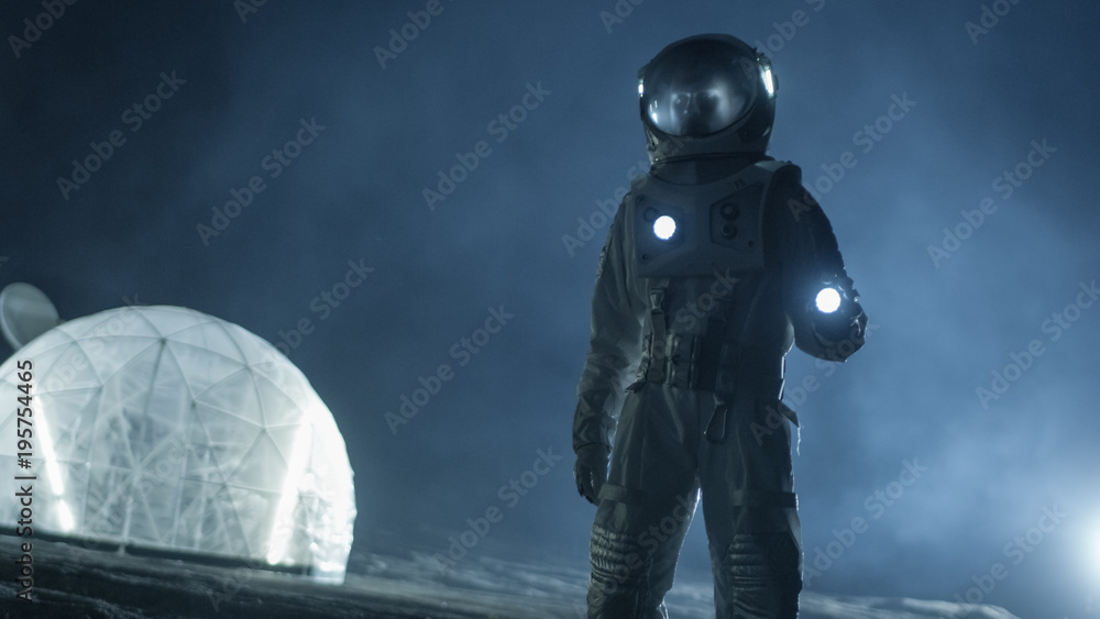 Courageous Astronaut in the Space Suit Holds Flashlight and Explores Misty Alien Planet. In the Background Living Habitat. Space Travel, Habitable World and Colonization Concept. Courageous Astronaut in the Space Suit Holds Flashlight and Explores Misty Alien Planet. In the Background Living Habitat. Space Travel, Habitable World and Colonization Concept.