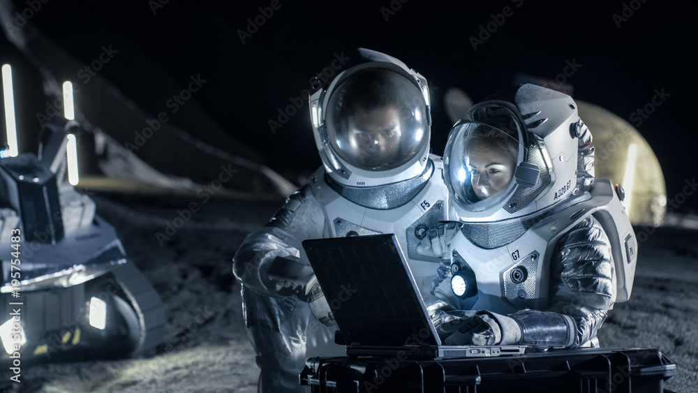 Two Astronauts Wearing Space Suits Work on a Laptop, Exploring Newly Discovered Planet, Send Communicating Signal to Earth. Space Travel, Interstellar Exploration and Colonization Concept. - obrazy, fototapety, plakaty 
