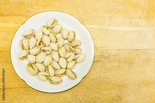 Plate with roasted pistachios in shell. View from above.