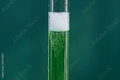 стеклянная пробирка с зелёной жидкостью и белой пене