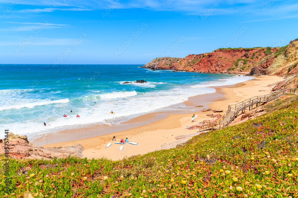 Surfers on beautiful Praia do Amado beach, popular place to do water sports, Algarve, Portugal