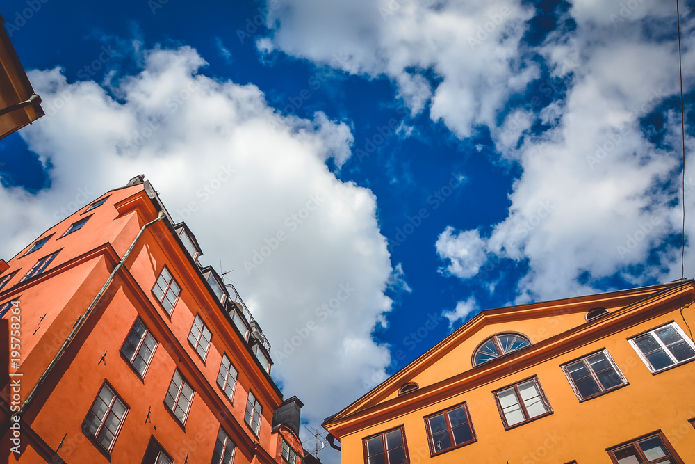 Orange and red building with many windows in the city of Stockholm, Sweden on a sunny summer day against a background of cloudy and contrasting sky