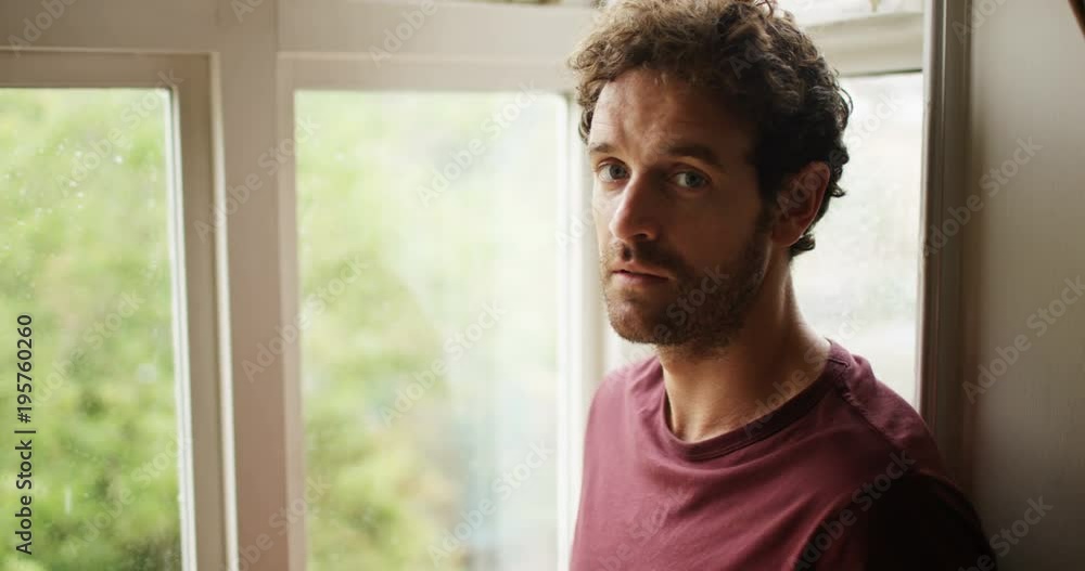 4K Depressed man staring out of window on a rainy day turns to look at camera. Slow motion. 4K Depressed man staring out of window on a rainy day turns to look at camera. Slow motion.
