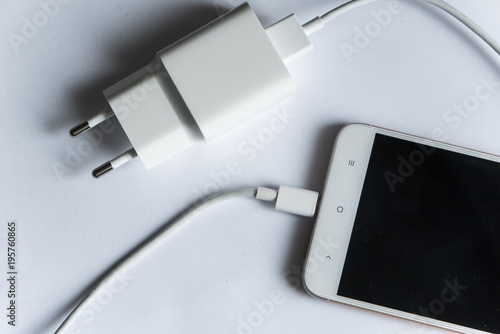 Smartphone with charger on white background