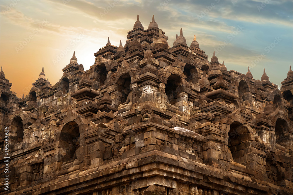 Ancient sculptures and statues on the walls of the Borobudur temple against sunrise.  Indonesia. Java island.