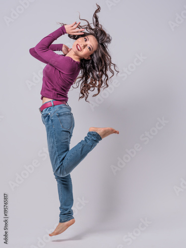 Beautiful Female Asian Model in blue jeans and pruple top jumping with hair flying photo