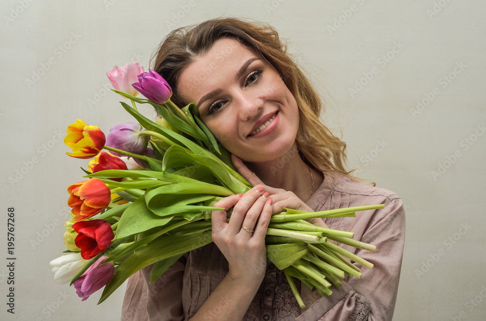 Young charming girl with a bouquet of flowers - multi-colored tulips Young charming girl with a bouquet of flowers - multi-colored tulips