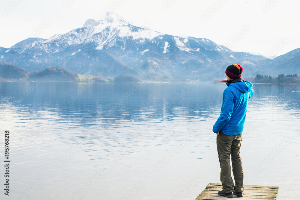 The man looking at the mirror lake and the mountains at the background with clear sky in cold weather