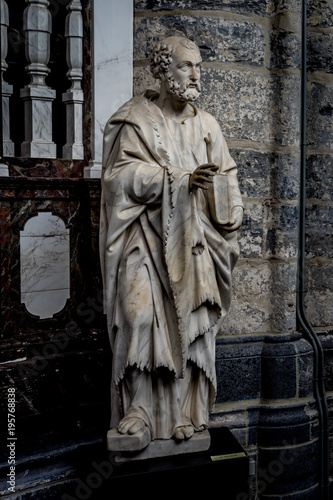 A white marble sculpture of an Scholar with a book in the interiors of Saint Nicholas Church, Ghent, Belgium