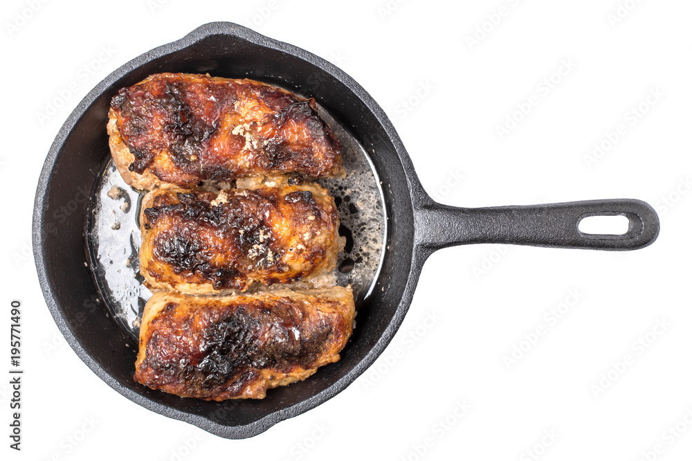 Roasted chicken pieces in cast iron pan top view, isolated